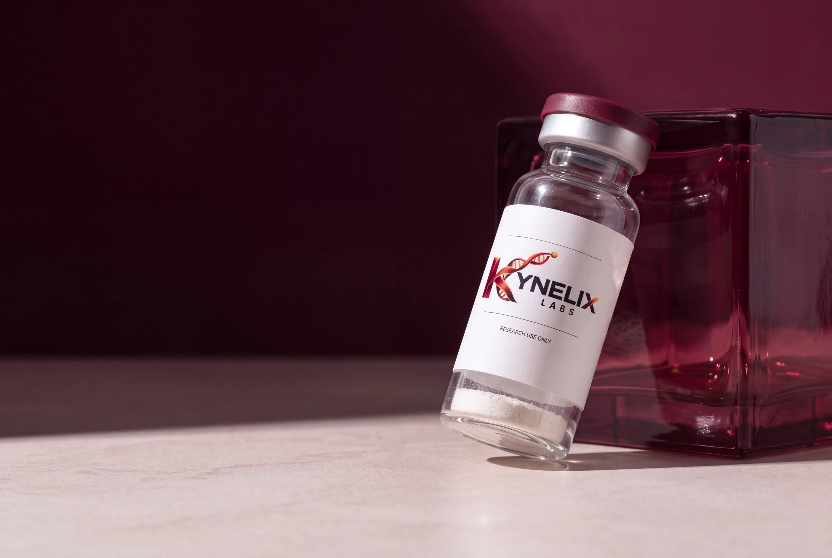 Kynelix glass vial with a burgundy cap and one low white powder puck at the inside bottom